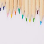 Wooden colored pencils lined up with a white background